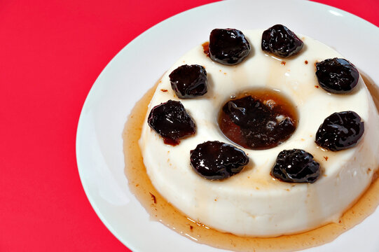 Delicious traditional Brazilian dessert known as "Manjar de Coco Branco" with plum sauce. Traditionally consumed at Christmas and New Year in Brazil. Isolated on red background. Copy space.