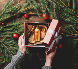 Female hands packaging cosmetics in a box next to Christmas decoration