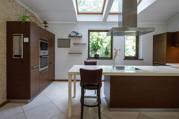 Modern interior of kitchen in spacious luxury apartment. Wooden kitchen set with white counter.