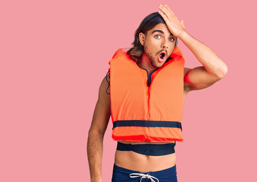 Young handsome man wearing nautical lifejacket surprised with hand on head for mistake, remember error. forgot, bad memory concept.