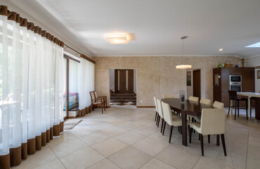 Modern interior of spacious kitchen in luxury private house. Wooden table and chairs. Panorama windows.