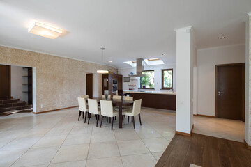 Contemporary interior of kitchen in luxury apartment. Wooden kitchen set. Huge table and cozy chairs. Private house.