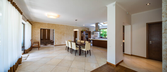 Contemporary interior of kitchen. Wooden kitchen set. Huge table and cozy chairs. Private house.