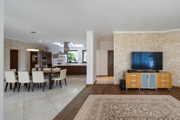 Luxury interior of spacious studio apartment. Wooden kitchen set. Table and chairs. TV on chest of drawers.