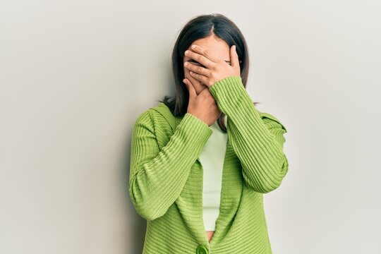 Young brunette woman wearing casual clothes covering eyes and mouth with hands, surprised and shocked. hiding emotion