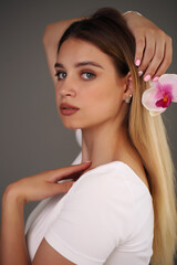 Fototapeta premium Beauty Portrait. Beautiful Stylish Girl with Orchid Flower. Perfect Face Skin. Healthy hair.