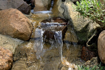 Kaskada wodna zbudowana z naturalnych kamieni i skał w przydomowym ogrodzie  