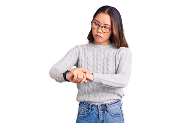 Young beautiful chinese girl wearing casual clothes checking the time on wrist watch, relaxed and confident