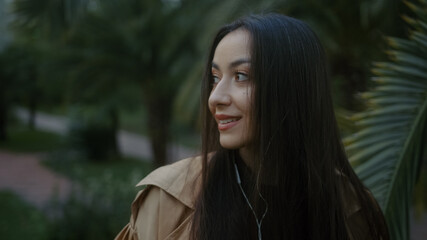 Sweet young pretty woman is texting and looking around while listening to music with her phone,...