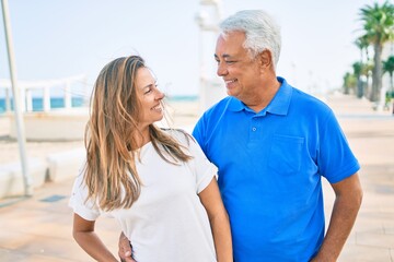 Middle age hispanic couple smiling happy hugging at the promenade.