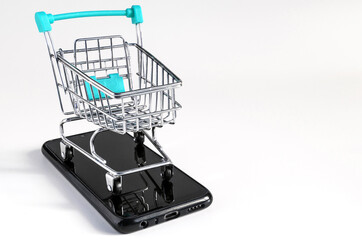 blue trolley at the supermarket, standing on the smartphone on a light background, the concept of online trading