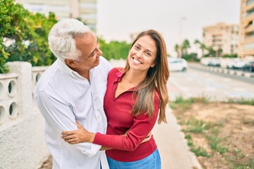 Fototapeta premium Middle age hispanic couple smiling happy and hugging walking at street.