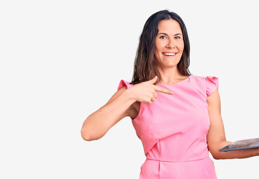 Young beautiful brunette woman working using laptop pointing finger to one self smiling happy and proud