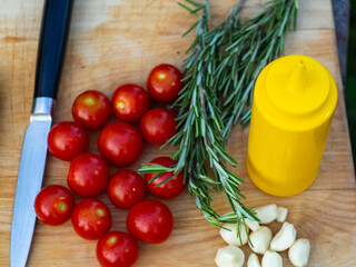 rosemary, cherry tomatoes, garlic on a wooden Board. cooking sauce for meat.