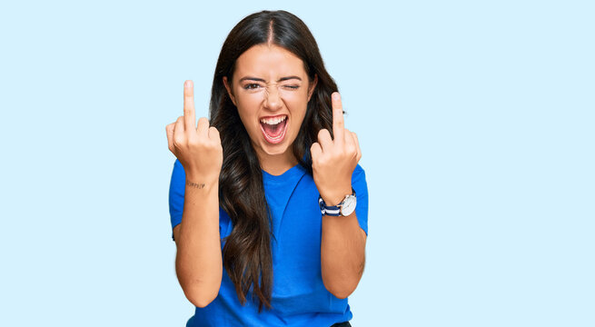 Beautiful brunette young woman wearing casual clothes showing middle finger doing fuck you bad expression, provocation and rude attitude. screaming excited