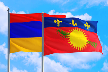 Naklejka premium Guadeloupe and Armenia national flag waving in the windy deep blue sky. Diplomacy and international relations concept.