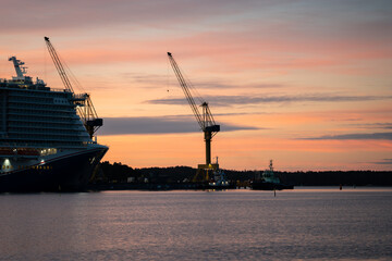 Fototapeta premium Bow of cruise ships and cranes at sunrise