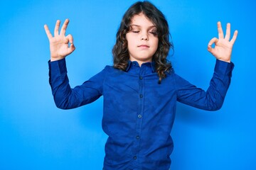 Cute hispanic child with long hair wearing casual clothes relax and smiling with eyes closed doing meditation gesture with fingers. yoga concept. © Krakenimages.com
