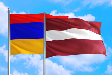 Fototapeta na wymiar Latvia and Armenia national flag waving in the windy deep blue sky. Diplomacy and international relations concept.