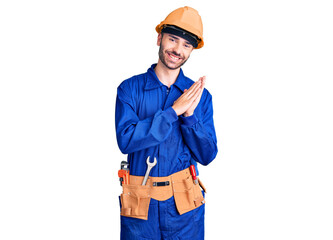 Young hispanic man wearing worker uniform clapping and applauding happy and joyful, smiling proud hands together