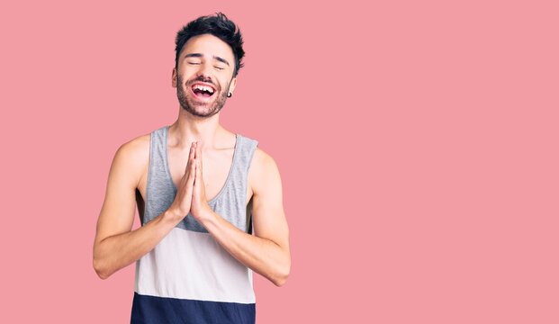 Young hispanic man wearing casual clothes praying with hands together asking for forgiveness smiling confident.