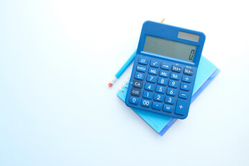 Close up of blue calculator and notepad on color background  - obrazy, fototapety, plakaty