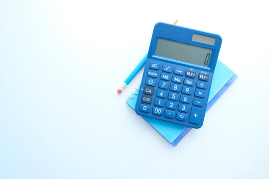 Close up of blue calculator and notepad on color background 
