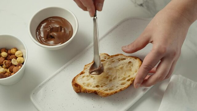 Young girl spreads chocolate peanut butter on croissant with vintage knife