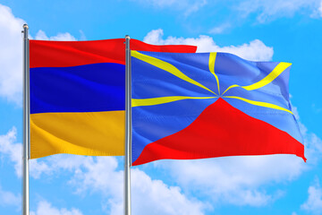 Reunion and Armenia national flag waving in the windy deep blue sky. Diplomacy and international relations concept.