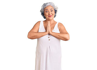 Senior woman with gray hair wearing casual clothes praying with hands together asking for forgiveness smiling confident.