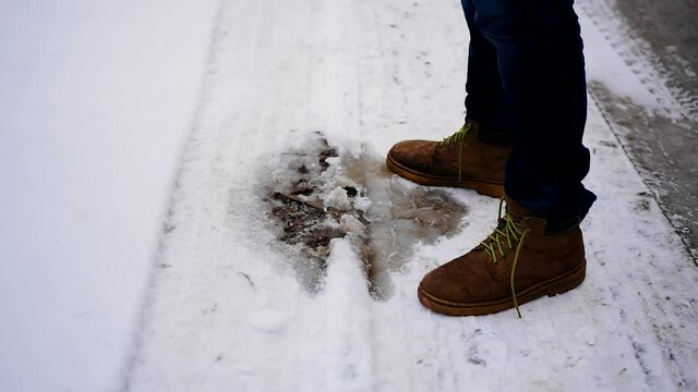 The guy pees on the snow near his shoes. Close up.