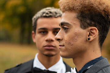 Profile portrait of handsome young gay man of color with his boyfriend blurred in the background. Concept of same sex love, equality and LGBT rights. Black lives matter!