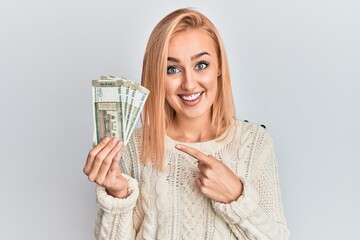 Beautiful caucasian woman holding 500 indian rupee banknotes smiling happy pointing with hand and finger