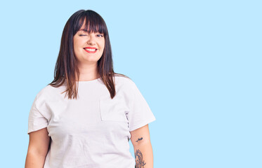 Young plus size woman wearing casual clothes winking looking at the camera with sexy expression, cheerful and happy face.