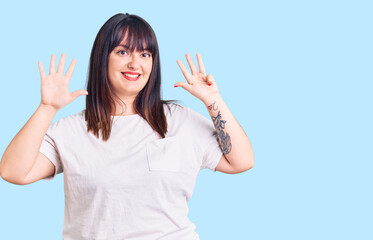 Young plus size woman wearing casual clothes showing and pointing up with fingers number nine while...