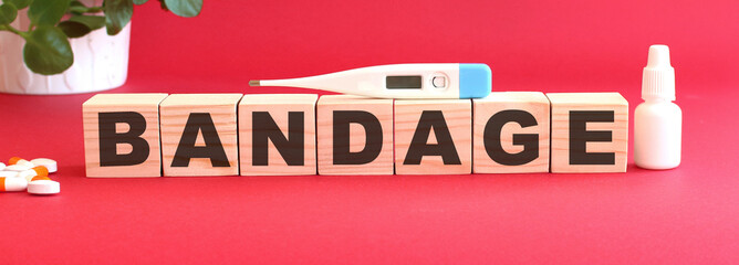 The word BANDAGE is made of wooden cubes on a red background. Medical concept.