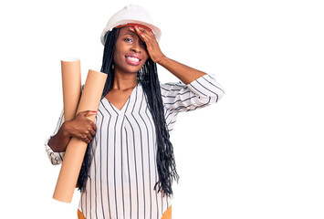 Fototapeta premium Young african american woman wearing architect hardhat holding blueprints stressed and frustrated with hand on head, surprised and angry face