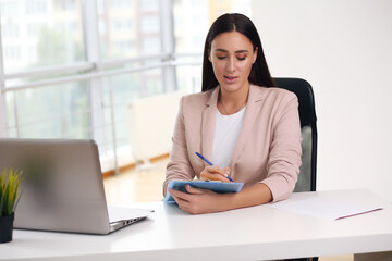 Obraz premium Young female content manager makes notes with a pen