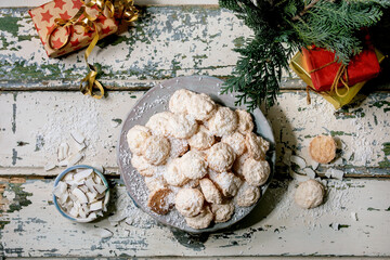 Homemade Christmas coconut gluten free cookies with coconut flakes on ceramic plate on old wooden table with xmas gifts and decorations. Flat lay
