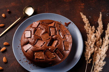 Chocolate cake with chocolate pieces on a brown background