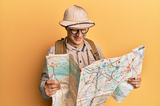 Middle age bald man wearing explorer hat holding map smiling with a happy and cool smile on face. showing teeth.