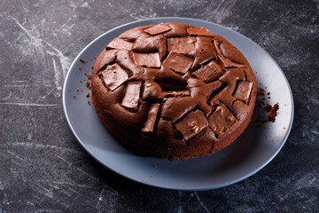 Chocolate cake with chocolate pieces on a metallic black background