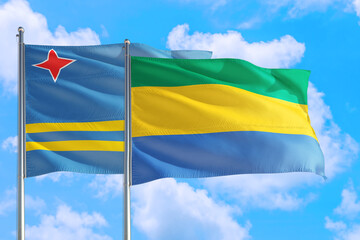Gabon and Aruba national flag waving in the windy deep blue sky. Diplomacy and international relations concept.