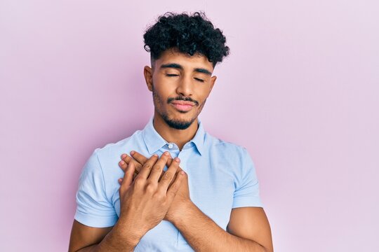 Young arab handsome man wearing casual clothes smiling with hands on chest, eyes closed with grateful gesture on face. health concept.