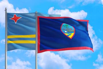 Guam and Aruba national flag waving in the windy deep blue sky. Diplomacy and international relations concept.