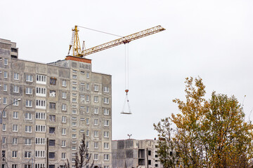 Fototapeta na wymiar Construction site with the high cranes building a grey block house in the city.