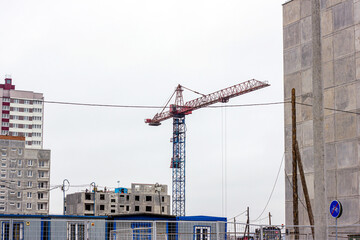 Construction site with the high cranes building a grey block house in the city.