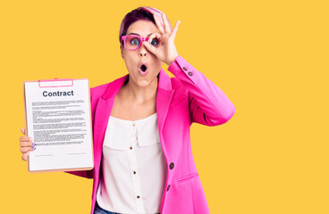 Young beautiful woman with pink hair holding clipboard with contract document doing ok gesture...