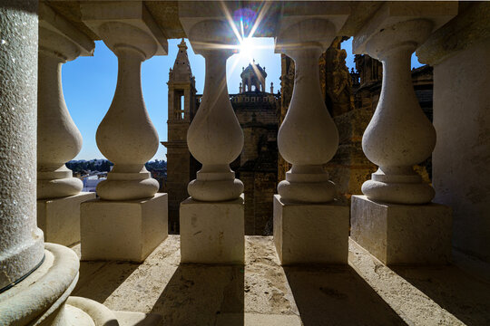 Vista de la catedral de Sevilla, la Giralda, desde un balc&oacute;n de piedra con el sol de frente a contraluz.