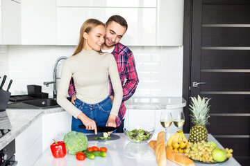 Picture of cheerful young couple in the kitchen hugging while cooking.